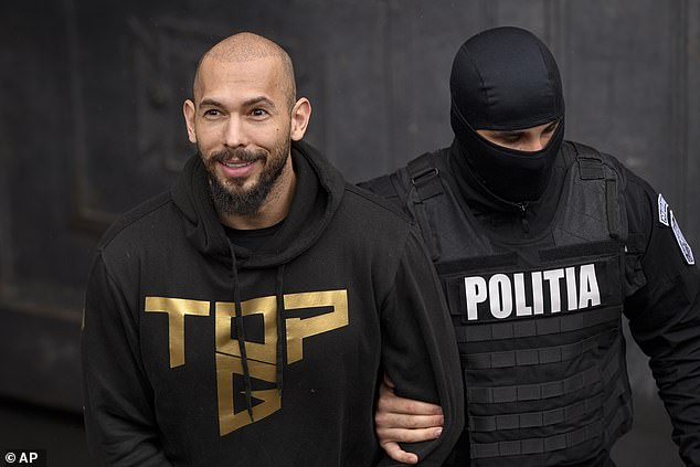 Pictured: A police officer escorts Andrew Tate, center, in handcuffs, from the Court of Appeal in Bucharest, Romania, Tuesday, March 12, 2024.