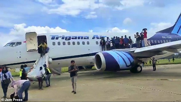 The image shows people escaping from a plane via an emergency slide after a passenger saw smoke coming from the plane's engine.