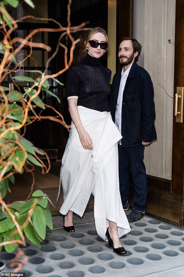 Her first look featured a thin, semi-sheer black turtleneck sweater that she wore over a white short-sleeved blouse. She brightened up the dark top with her flowy white culottes.