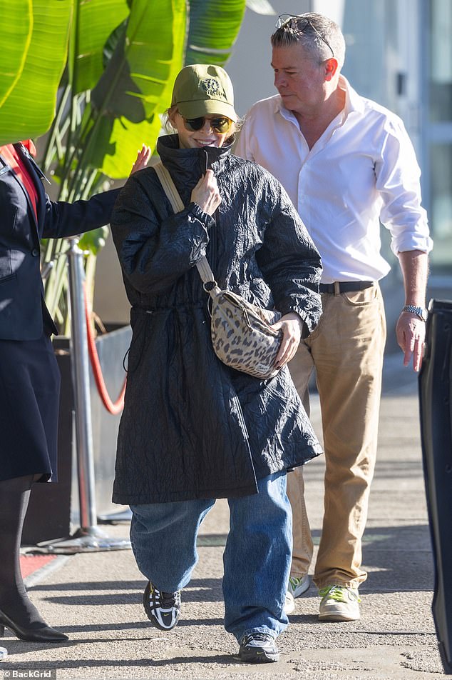 The Australian pop legend, 58, donned a large black coat over a loose-fitting T-shirt paired with casual jeans and black sneakers.