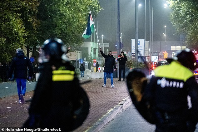 A protester with a Palestinian flag and a Mobile Unit (ME) during a pro-Palestinian demonstration during the Ajax - Maccabi Tel-Aviv in Anton de Komplein