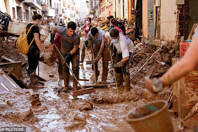 Volunteers and locals help clean mud from the street after heavy rain in Paiporta, near Valencia, Spain, on November 5, 2024.