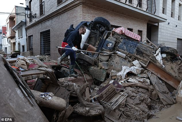 A man walks over rubble to access a mud-covered street in the flood-affected city of Paiporta, Valencia, Spain, on November 7, 2024.