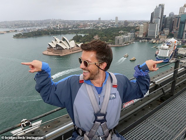 He took to Instagram to share a carousel of photos from his trip, including one of him climbing the world-famous Sydney Harbor Bridge (pictured).