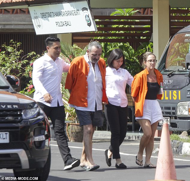 With heads bowed, Michael Le Grand and his wife Lynley parade in handcuffs outside Bali police headquarters after their arrest.