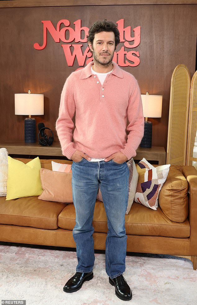 Brody was the picture of casual cool in blue jeans, a light red sweater, and black shoes.