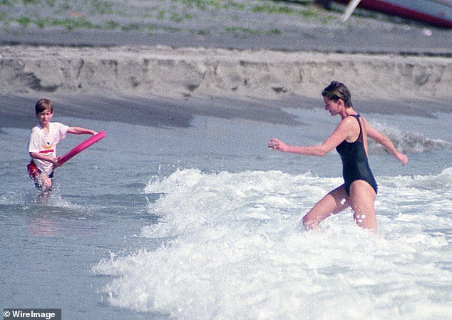 The late Princess of Wales walking through the waves towards Harry, who is holding a board.