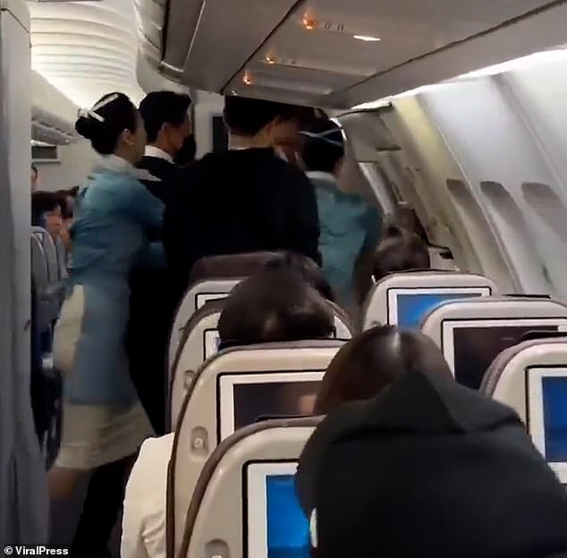 Several flight attendants try to grab the man when they see him heading towards the door.