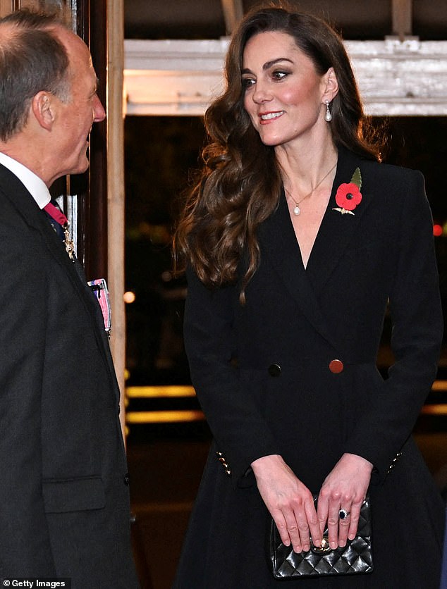 Always fashionable, Kate wore a mid-length black dress with a deep V-neck, fitted to her slender figure, accompanied by an elegant black clutch.