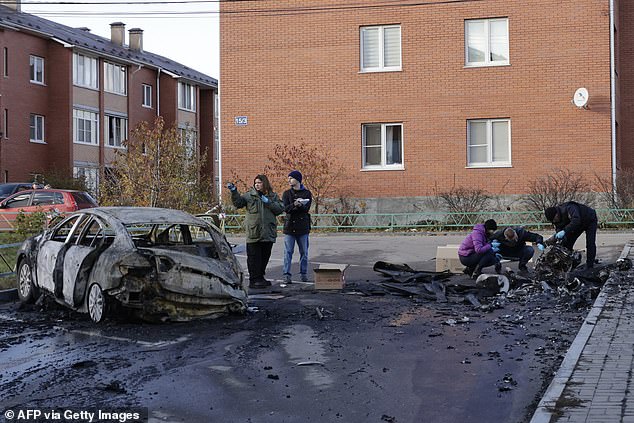 Russian police officers inspect the remains of a drone next to a burned-out car in the courtyard of residential buildings after a drone attack in the village of Sofyino, Moscow region, on November 10.