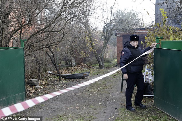 A Russian police officer places caution tape at the site of a drone strike in the village of Stanovoye, Moscow Region, on November 10.