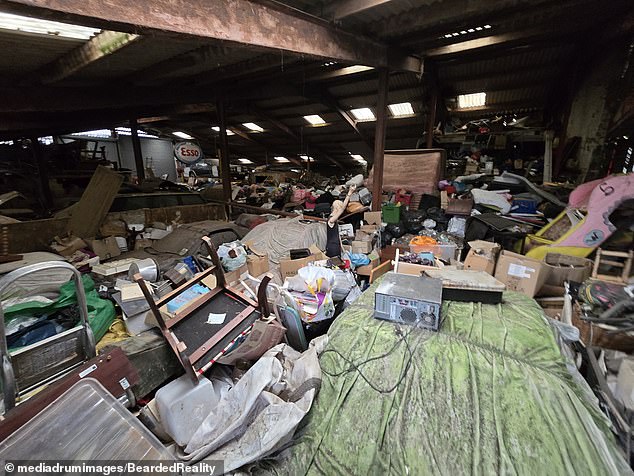 Piles of clutter fill one side of the barn that's packed with vintage cars