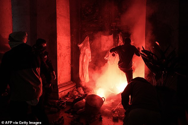 Protesters kick at the entrance of the town hall as a flare is lit during a demonstration to demand the resignation of Valencia regional president Carlos Mazón in Valencia on November 9, 2024.