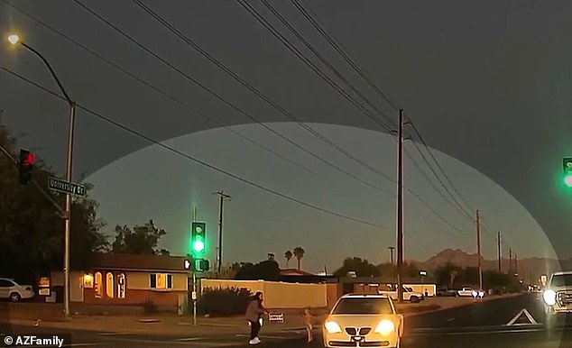 The woman filming bursts into howls as the toddler walks onto the road and a pickup truck swerves to narrowly avoid hitting them.