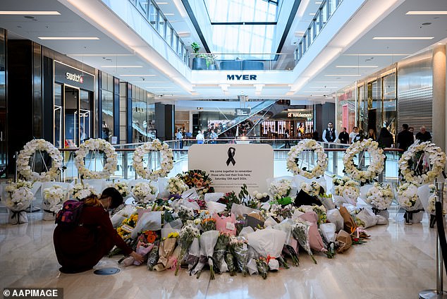 A member of the public places a flower at the Bondi Junction stabbing memorial site in the Westfield shopping center where it occurred.