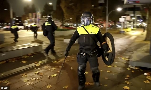 Police officers patrol in riot gear on the streets of Amsterdam following more violence.