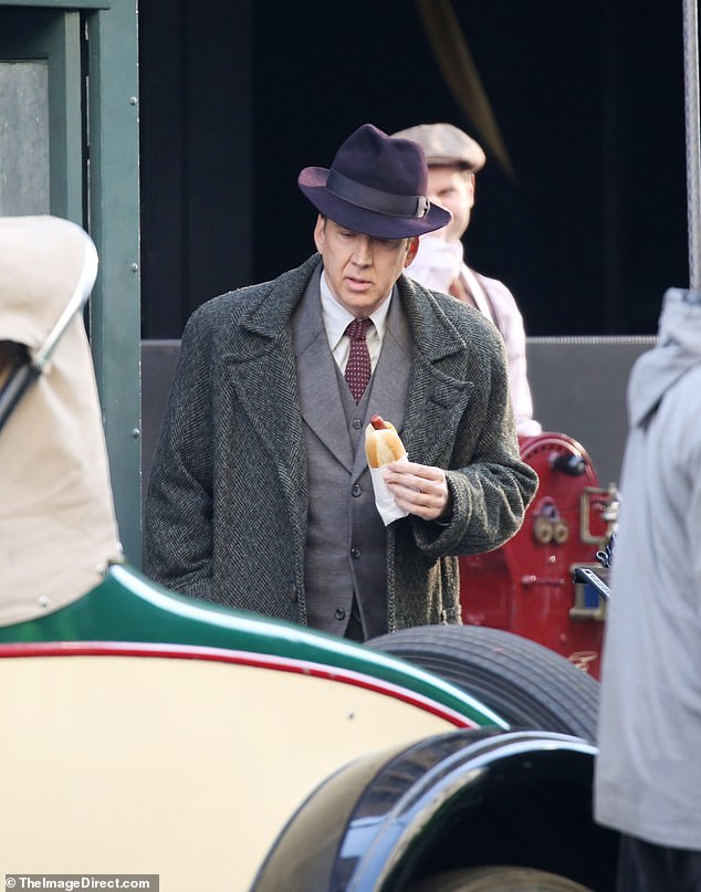 He was dressed as his character Spider-Man Noir, wearing a forest green coat, fedora and gray suit as he walked down a crowded street.