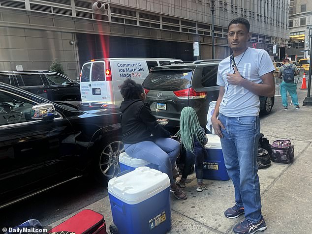 Asylum seeker Fernando Peralta, 34, sells drinks from a cooler outside the Roosevelt Hotel.