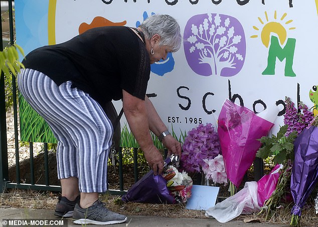 A woman leaves another floral tribute outside the preschool on Tuesday