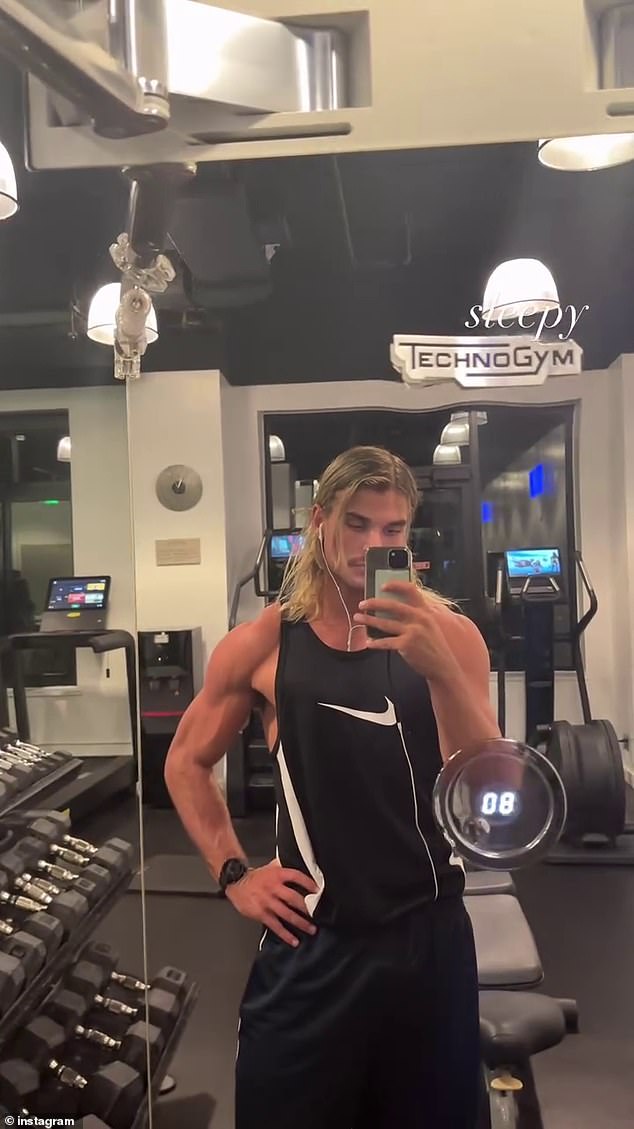 He was wearing a black Nike tank top that showed off his rippling biceps, delts, and chest muscles. His distinctive blonde mullet was on display, with some of the group tugging behind his ears as he worked his angles.