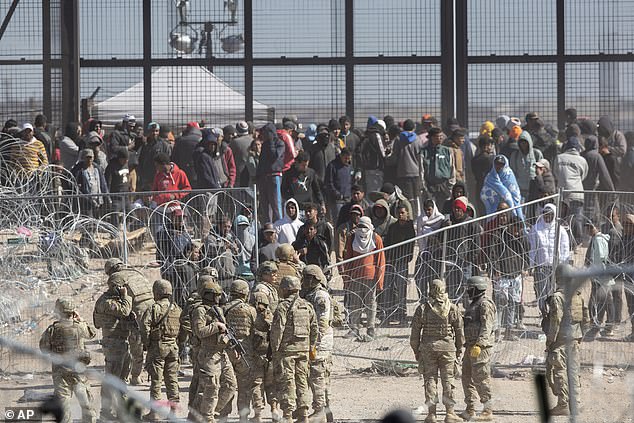 The Texas National Guard watches migrants after stranded barriers are set up on the Rio Grande in El Paso, Texas, on March 21, 2024.