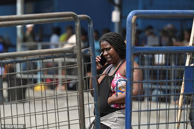 A woman talks on the phone while waiting for news of her loved one after at least 15 inmates were killed at the Litoral Penitentiary