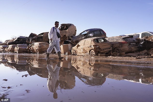 A man walks past stacked cars after flooding in Catarroja left hundreds dead or missing in the Valencia region of Spain, Tuesday, Nov. 12, 2024.