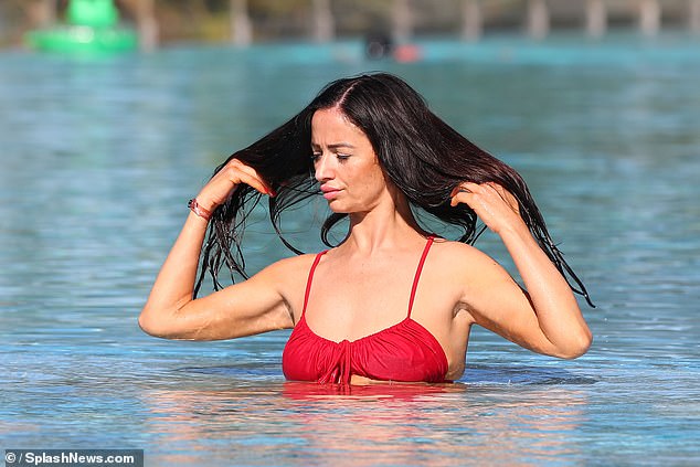 She let her brunette locks fall over her shoulders as she dipped them in the water.