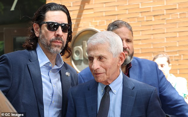 Fauci leaves the ABC studios while being escorted by his US Marshal's security team after appearing on 'The View' on Thursday. The Marshal can be clearly identified by his lapel pin.