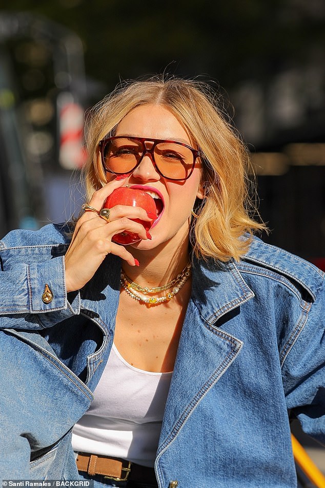 She also took a bite out of an apple in a cheeky reference to New York City, made a call from an old-school lip-shaped phone, and showed off her blood-red manicure.