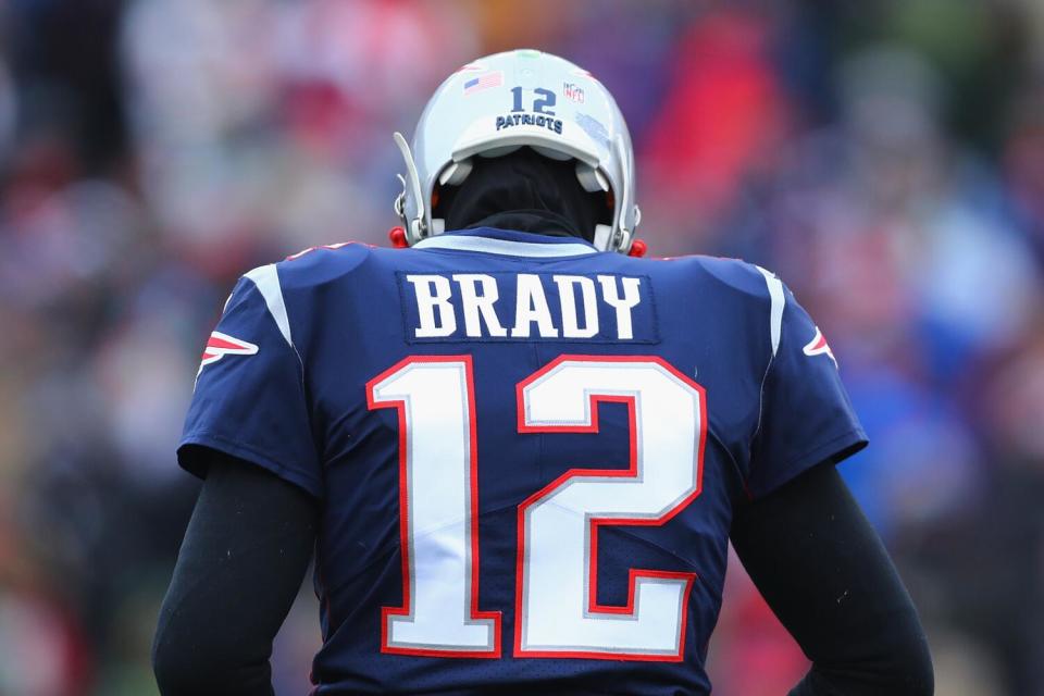 Tom Brady (12) of the New England Patriots is shown from behind with his badge visible.