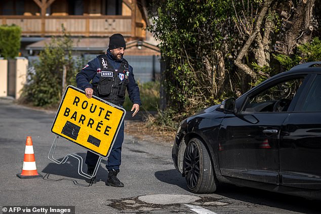 A surveillance officer closes the road to the village of Taninges, in the French Alps, where three children were found dead the day before, November 13, 2024.