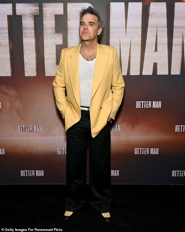 Robbie Williams turned heads in a yellow jacket while posing on the red carpet for the screening of his biopic Better Man in New York City on Wednesday.