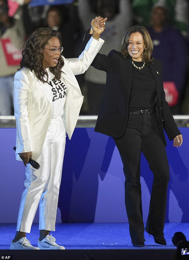 Oprah Winfrey holds hands with Kamala Harris after introducing the vice president to speak during a campaign rally outside the Philadelphia Museum of Art.