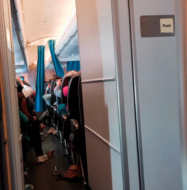 Passengers are seen clinging to the backs of their seats as the plane was rocked by extreme turbulence.