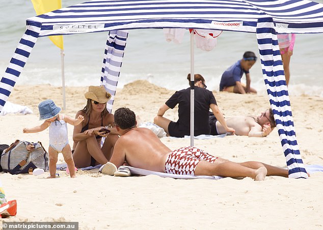 After the dip, it was time to rest, with the family retreating under the shade of a blue and white striped beach pergola.