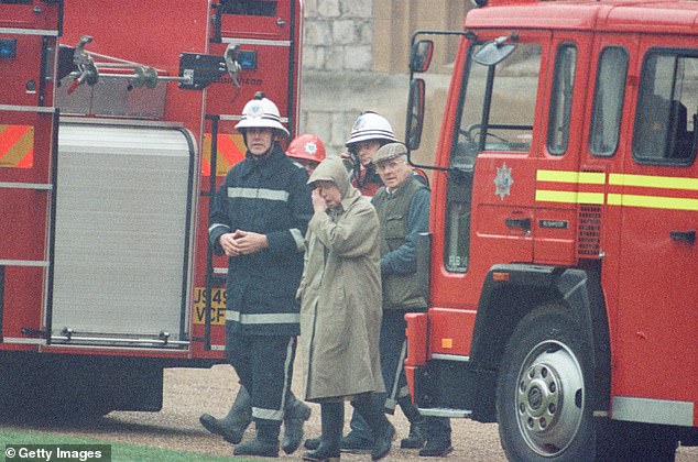 The Queen is escorted by a firefighter around the grounds while others fight the fire.