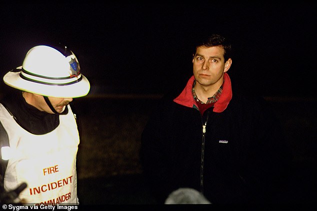 Prince Andrew, who was in the castle when the fire started and helped remove some of its contents, with a firefighter.