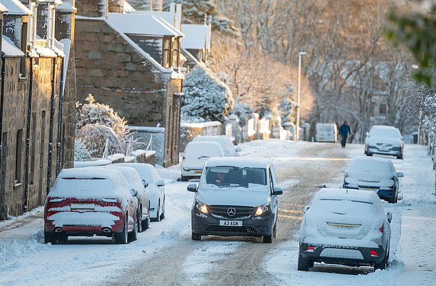 Pictured are cars driving through the snow on the A97 near Huntly, Aberdeenshire, this morning.