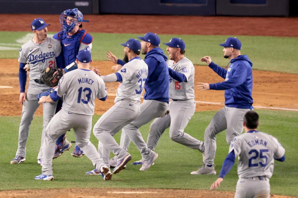 Players run to celebrate with Dodgers pitcher Walker Buehler after he threw the final out to win the World Series.