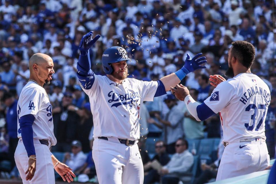 Dodgers third baseman Max Muncy is showered with sunflower seeds thrown by Teoscar Hernández after hitting a home run