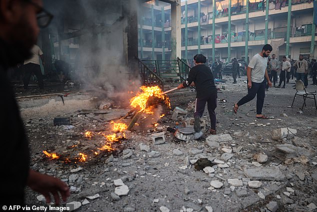 A young displaced Palestinian tries to control a fire in the rubble following an Israeli strike that hit a UN-run school where people had taken refuge, in the Nusseirat refugee camp in the central Gaza Strip on November 20 of 2024.