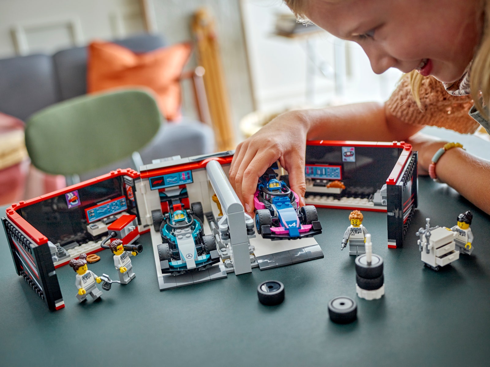 Boy playing with a Lego Formula 1 set with small building blocks that imitate a racing car garage