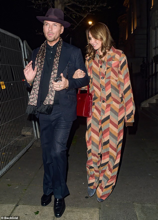 She looked chic in a beige printed jumpsuit and accessorized with a chic red bag as she held her arm as she left the chic venue.