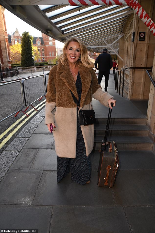 Claire Sweeney bundled up in a two-tone brown fluffy coat over a jumpsuit