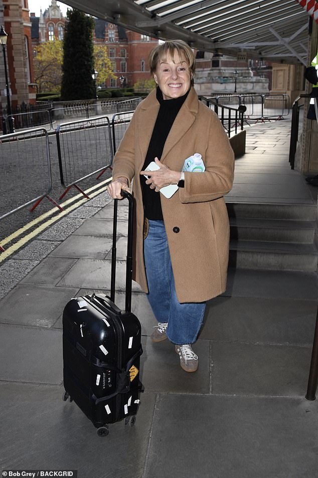 Sally Dynevor from Coronation Street wrapped up in a tan coat with a black jumper and jeans.