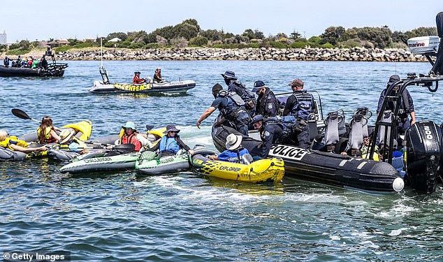 The climate protesters were arrested after failing to comply with a police directive to clear the shipping channel at Newcastle Harbor (pictured, police clash with protesters).