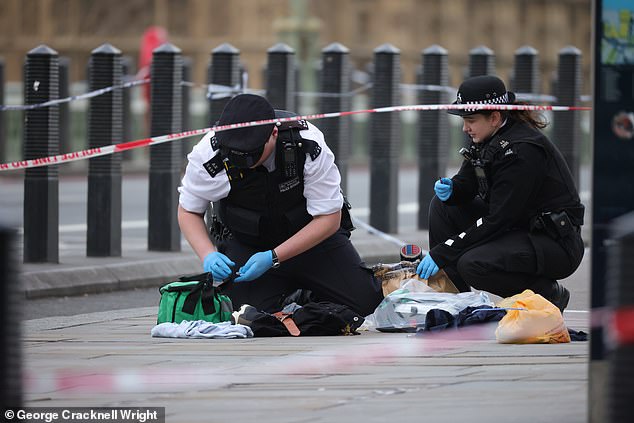 Police are pictured collecting evidence from the scene at Westminster Bridge today.