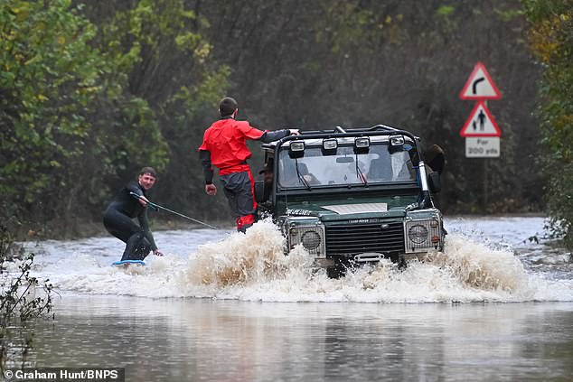 Young farmers with a 4x4 on Clay Lane near Chudleigh Knighton, near Newton Abbot in Devon, taking advantage of the flooding from Storm Bert to water ski along the submerged road