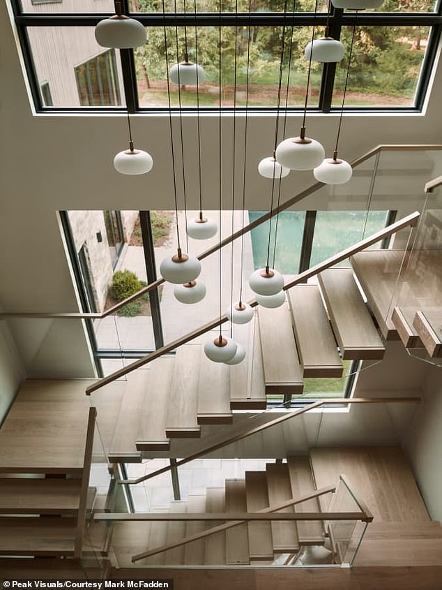 The Scandinavian-inspired design features a dramatic staircase with glass sides